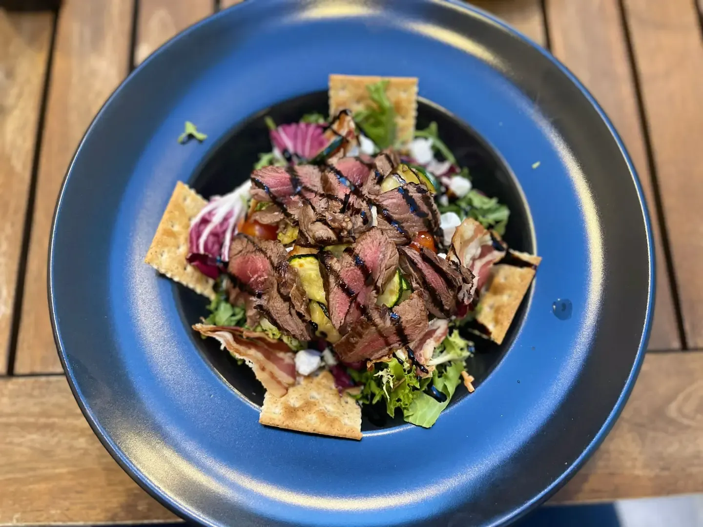 Beef salata na plavom tanjuru, na drvenom stolu