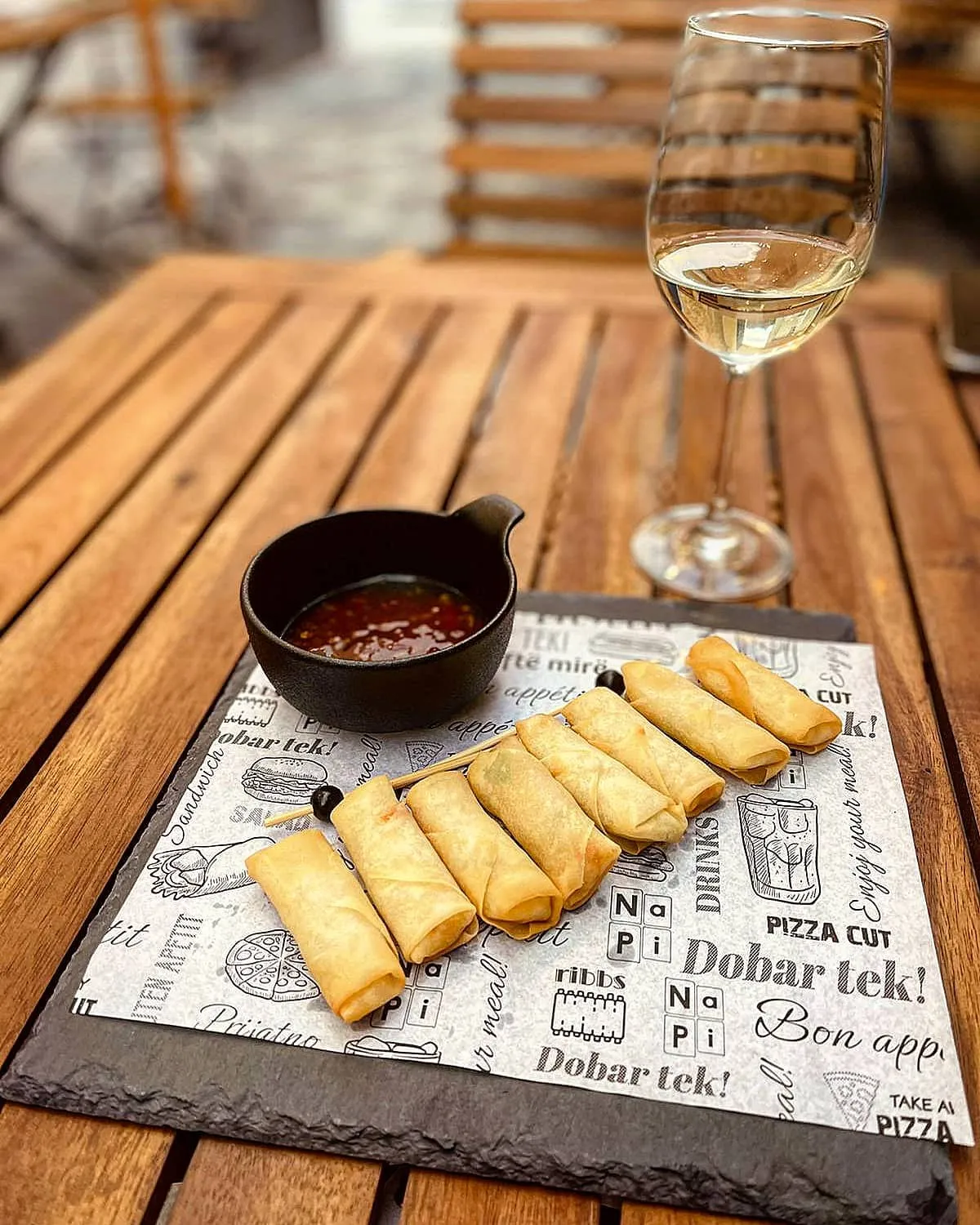 Springrolls s umakom i čaša vina na terasi